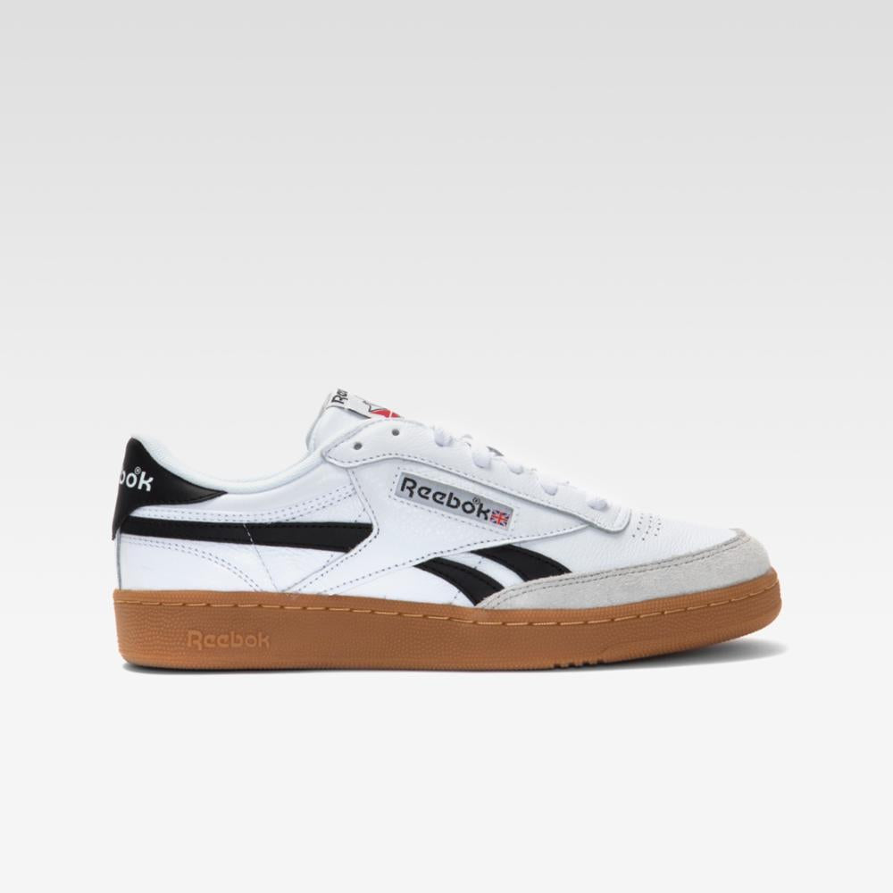 A white low-top sneaker with black stripes and a brown rubber sole.