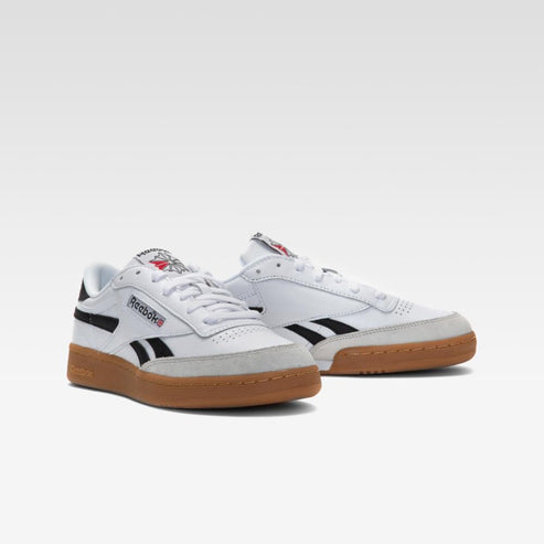 A pair of white low top shoes with black stripes and gum soles.