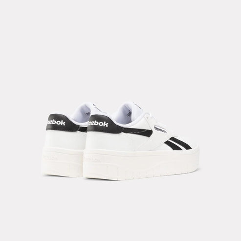 White platform sneakers with black accents and "Reebok" text on the side.