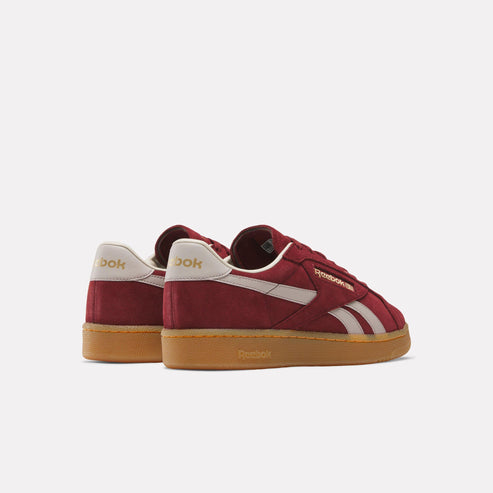 Low-top maroon sneakers with white stripes and tan soles, seen from behind.