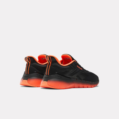 A pair of black athletic shoes with bright orange soles and trim.