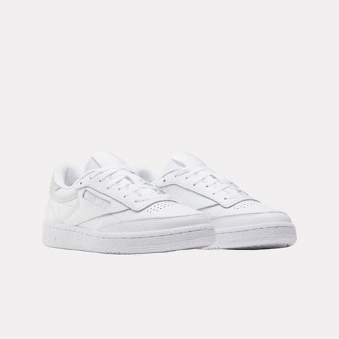 Pair of white low top sneakers with perforated toe box.
