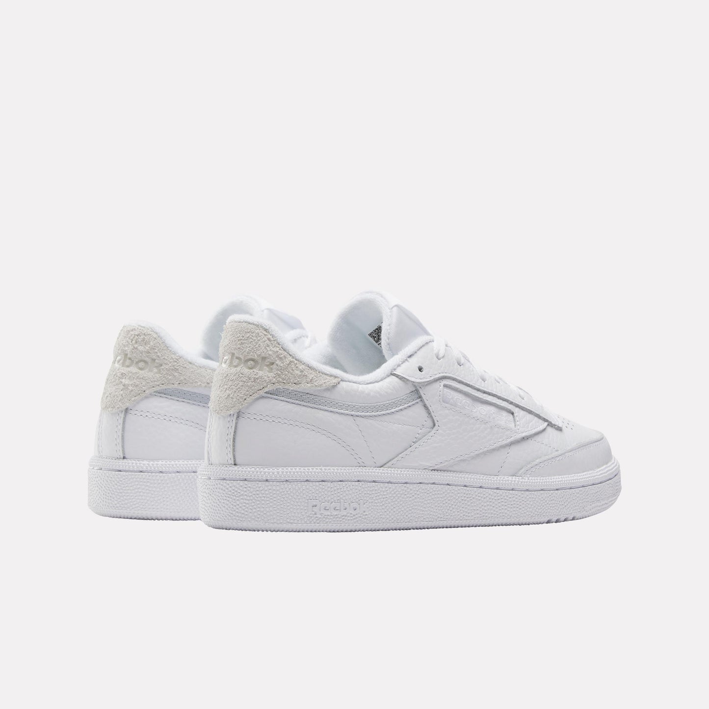 A pair of low top white sneakers with a textured heel.