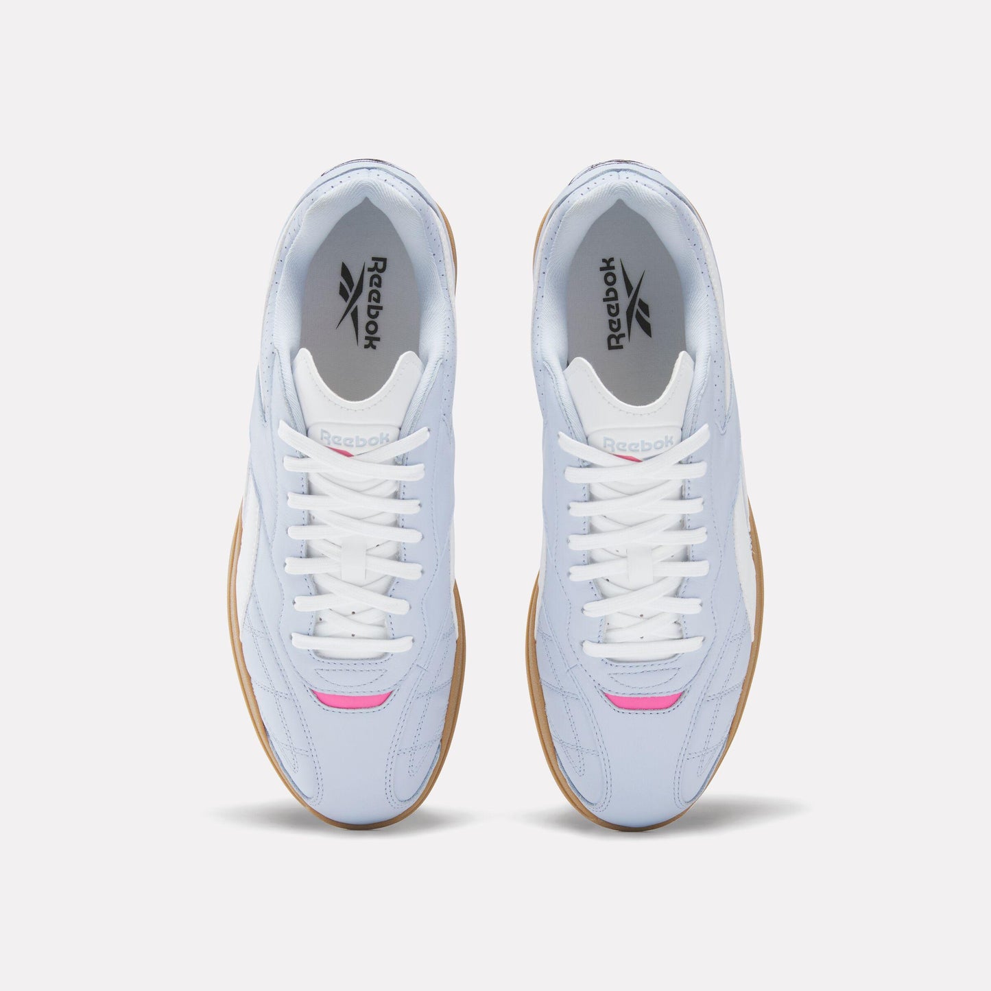 Overhead view of light blue sneakers with white laces and rubber soles.