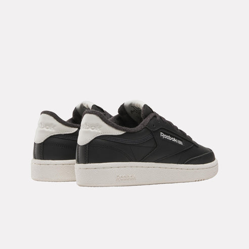 Low-top black sneakers with white logo and off-white soles.