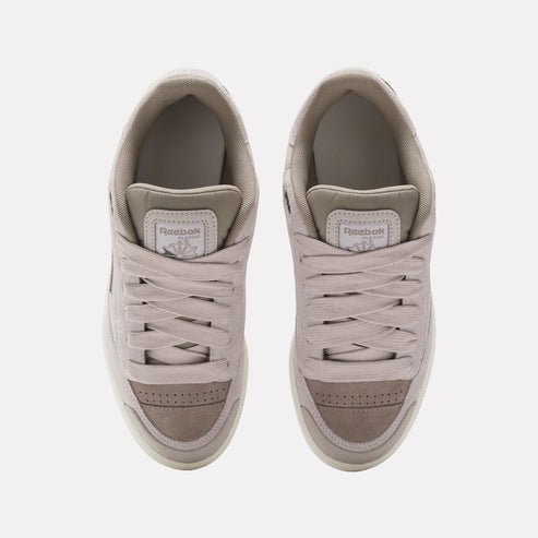 Overhead view of two beige sneakers with white laces. The tongue of each shoe has a Reebok logo.