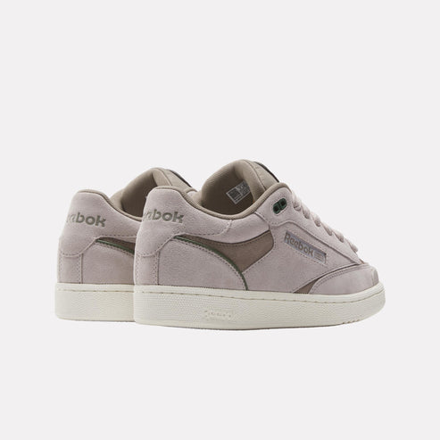 Low-top sneakers in gray suede with contrasting gray patch, stacked on a cream-colored sole, "Reebok" branding on the side and heel.