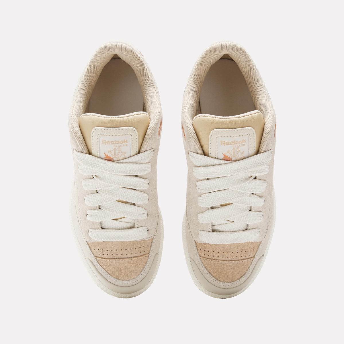 Top-down view of two cream-colored sneakers with white laces.