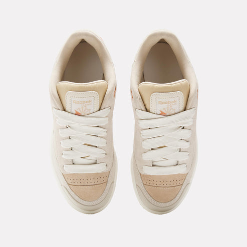Top-down view of two cream-colored sneakers with white laces.