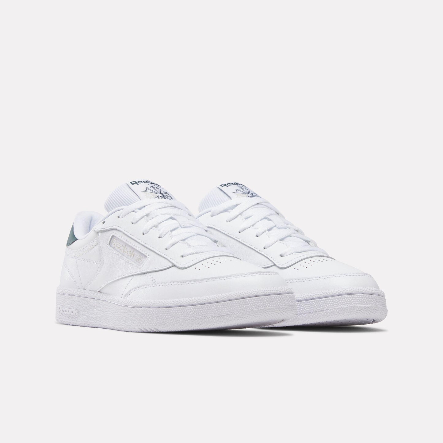 Pair of white low top sneakers with laces and a perforated toe.