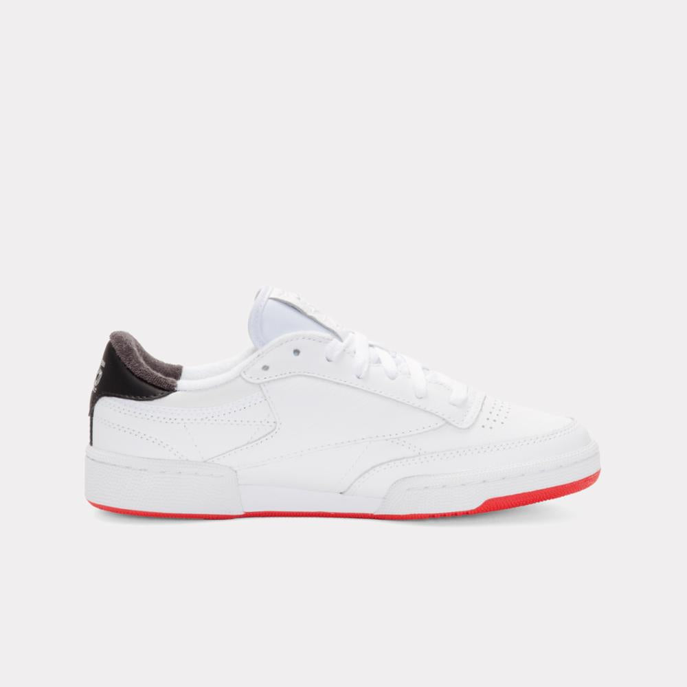 White tennis shoe with red sole and black heel.