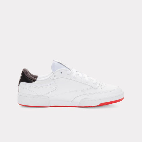 White tennis shoe with red sole and black heel.