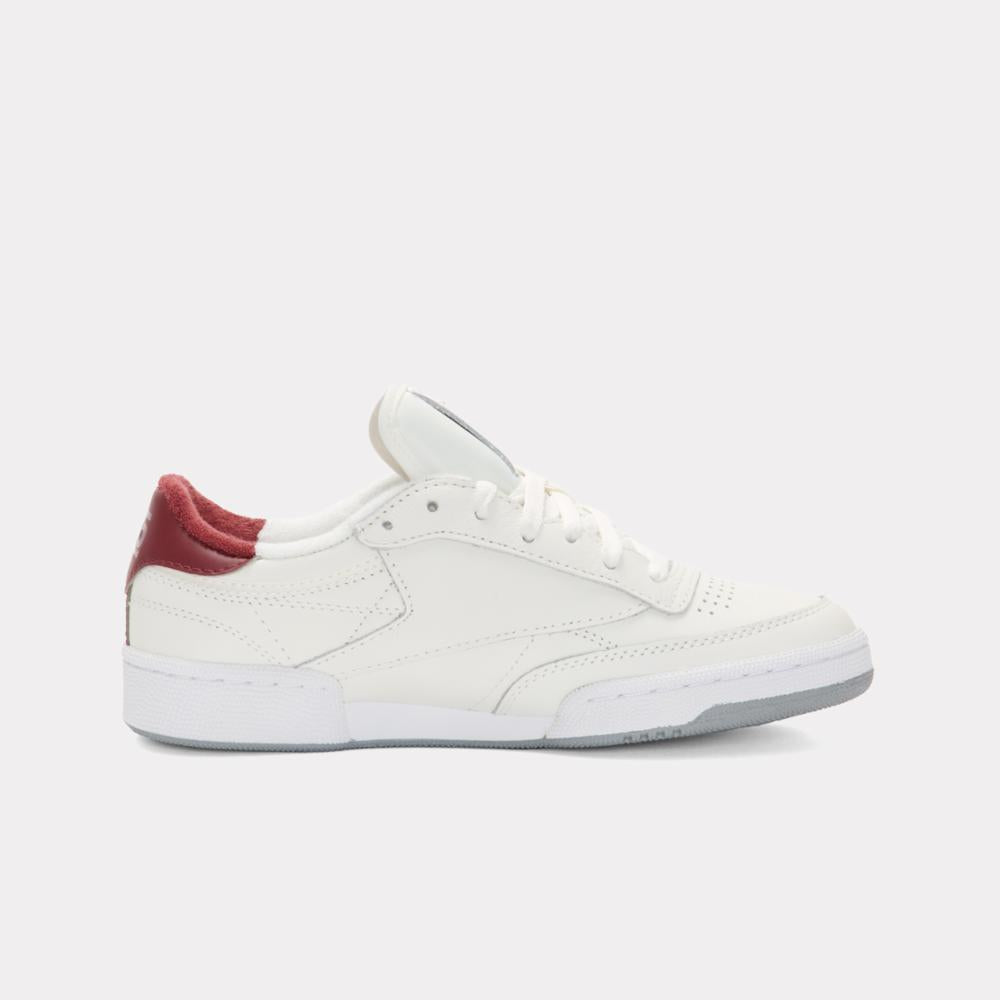 A white leather sneaker with a burgundy heel.