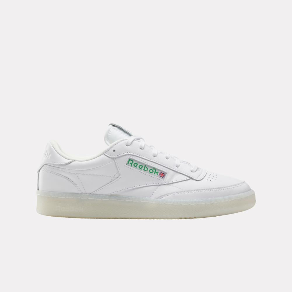 White leather sneaker with a translucent sole and the name "Reebok" in green and red letters.