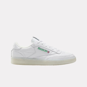 White leather sneaker with a translucent sole and the name "Reebok" in green and red letters.