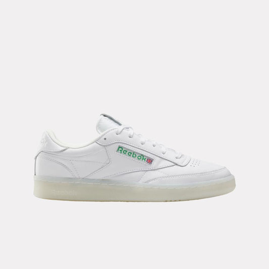 White leather sneaker with a translucent sole and the name "Reebok" in green and red letters.