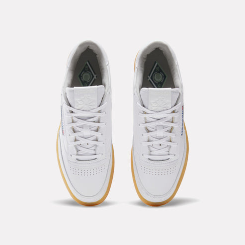 A pair of white sneakers with white laces and a tan rubber sole.