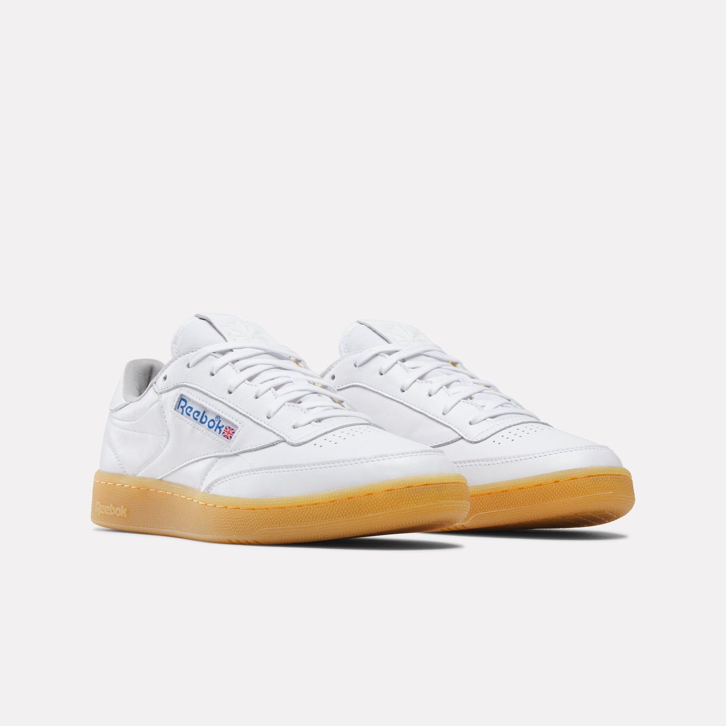 Two white leather tennis shoes with gum soles, seen at a slight angle.
