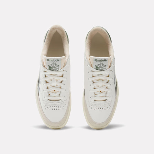 A pair of white sneakers with off-white soles, white laces, and visible logo on the tongue.