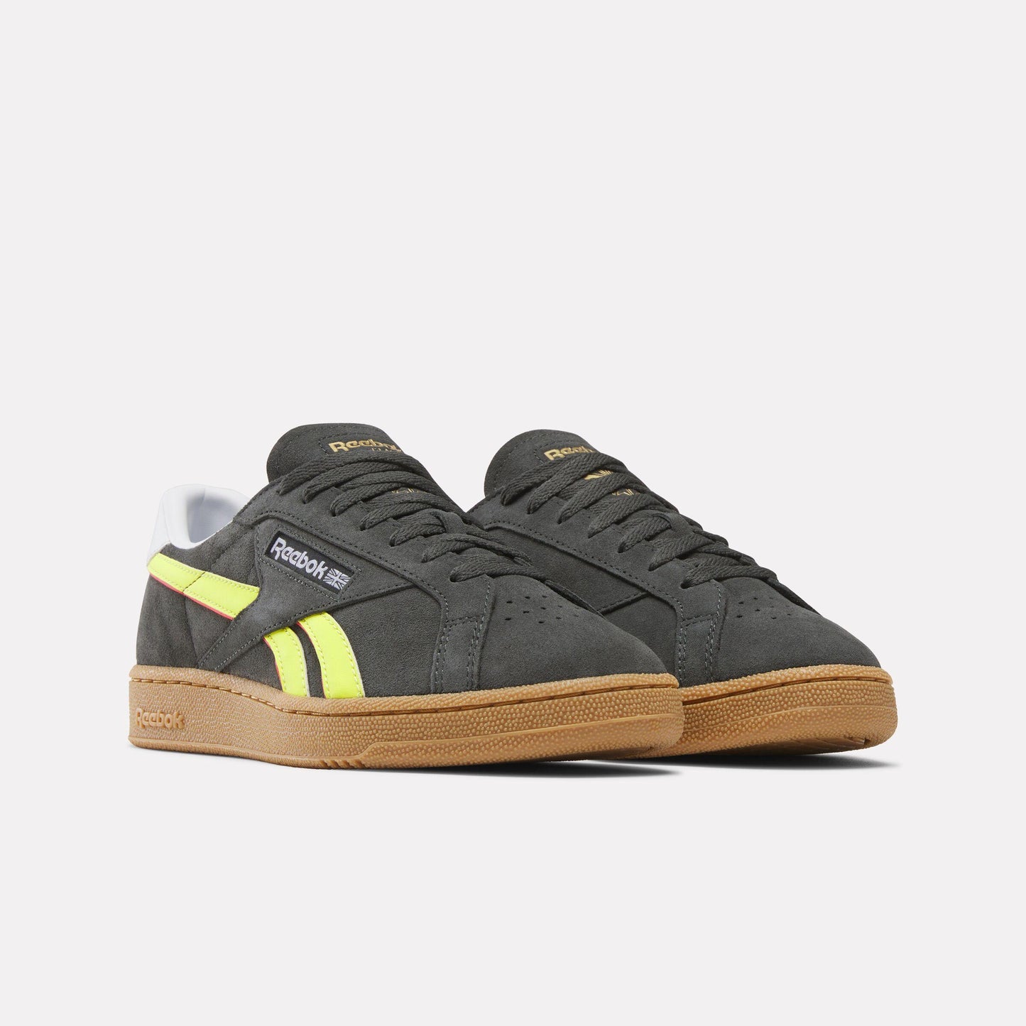 A pair of low-top gray sneakers with bright yellow accents and gum soles.