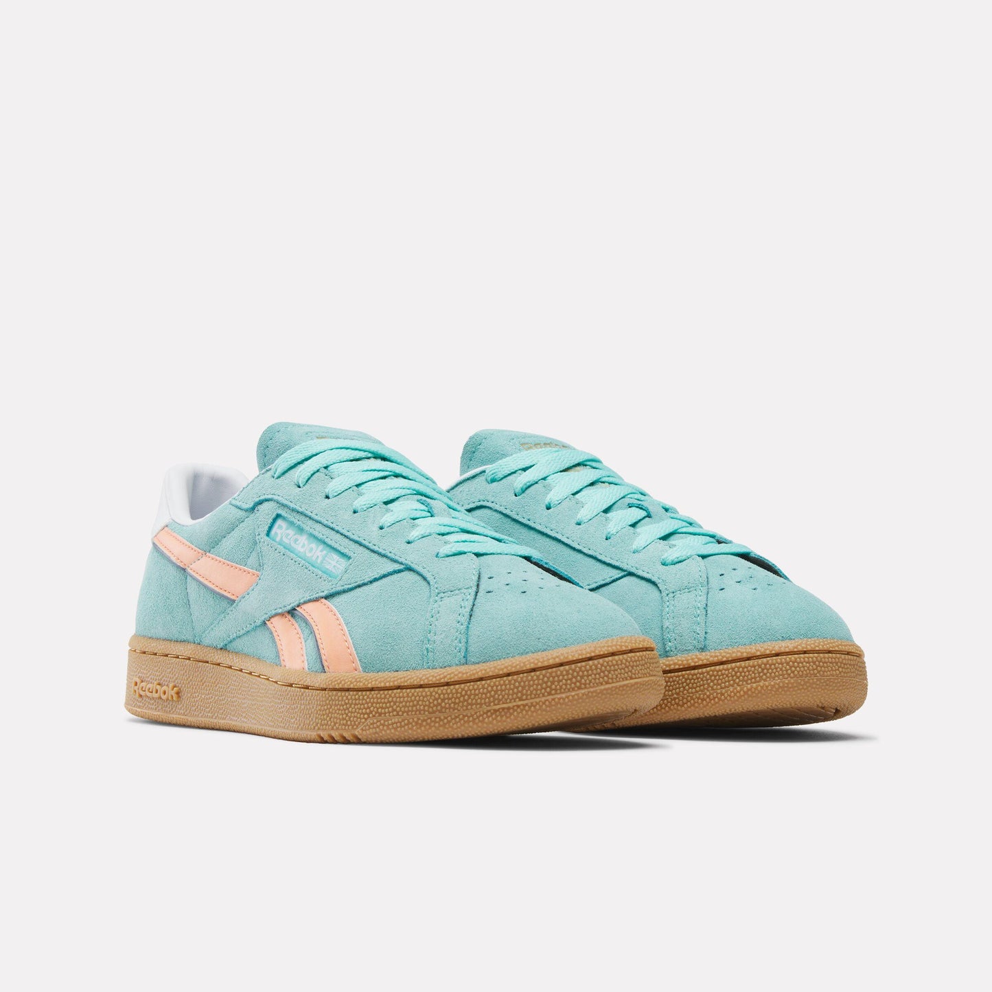 A pair of low-top, light blue suede sneakers with peach stripes and a light brown sole.