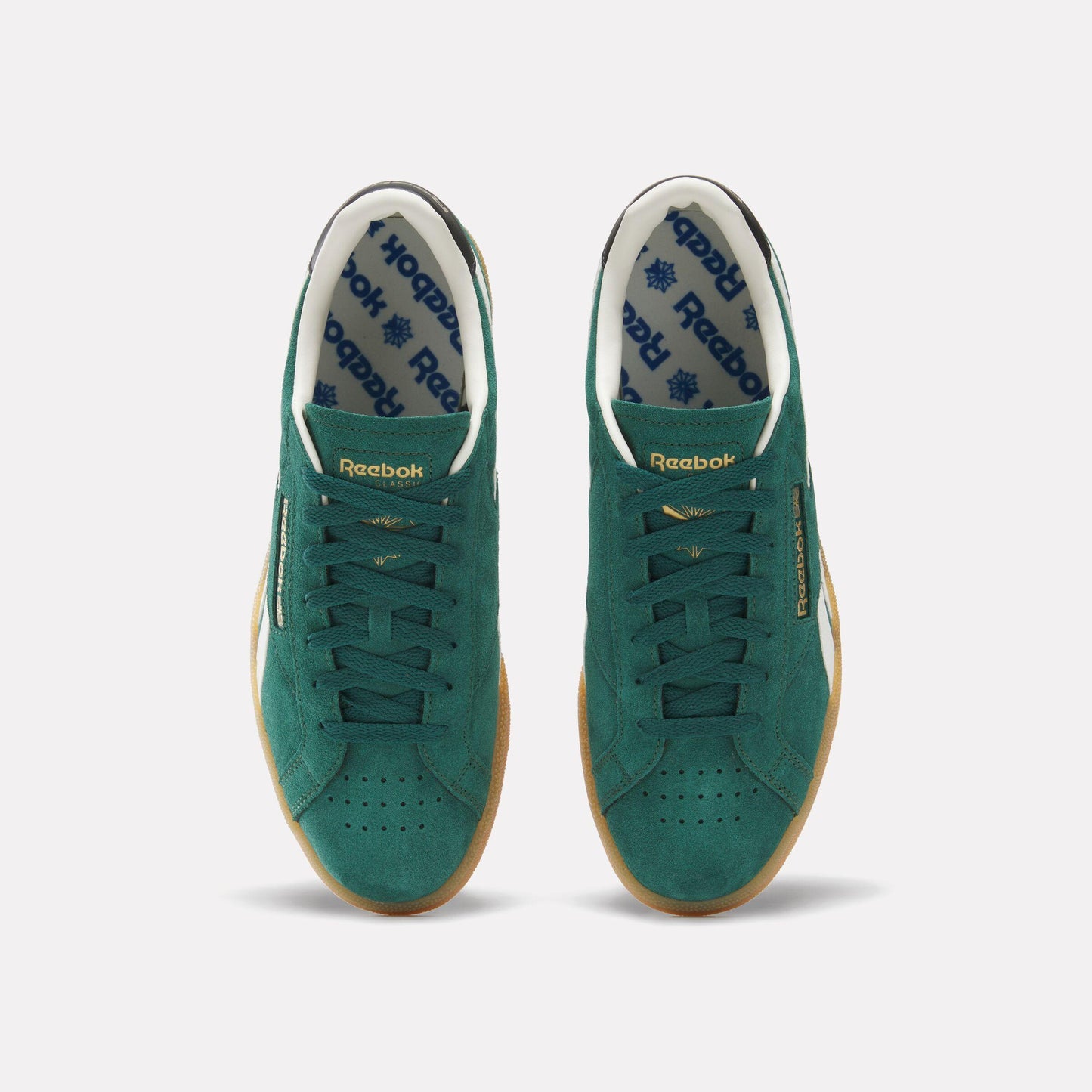 Overhead view of a pair of green suede sneakers with white and black accents, featuring a gum rubber outsole.