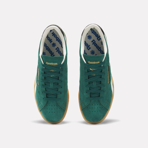 Overhead view of a pair of green suede sneakers with white and black accents, featuring a gum rubber outsole.