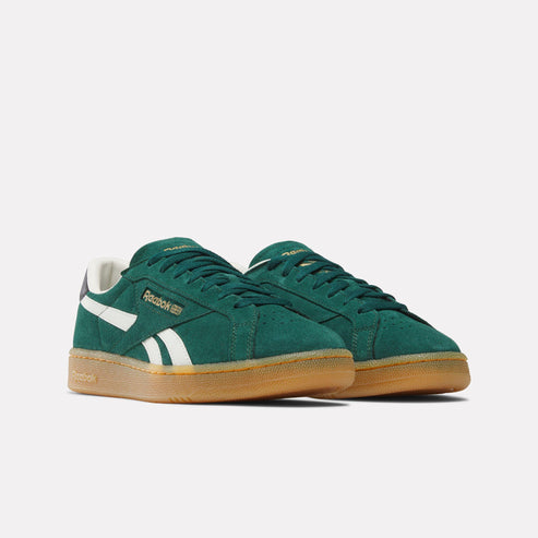 A pair of green suede sneakers with white stripes and gum soles, featuring "Reebok" in gold lettering.