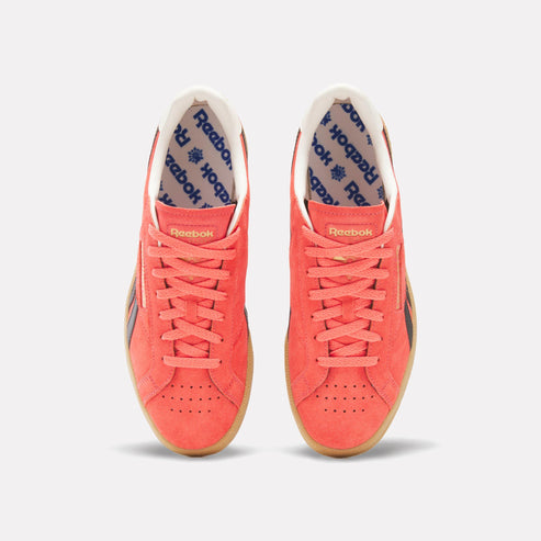 Two coral low-rise sneakers with white interior and gum sole.