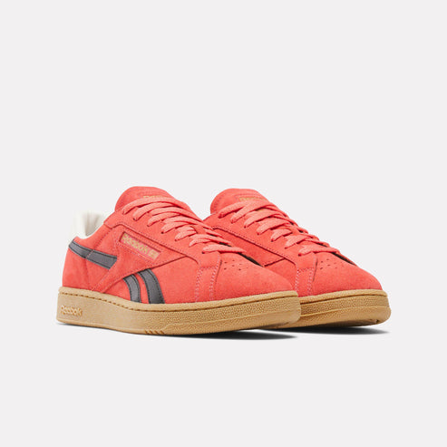 Pair of red suede tennis shoes with gum soles and black stripes on the sides.