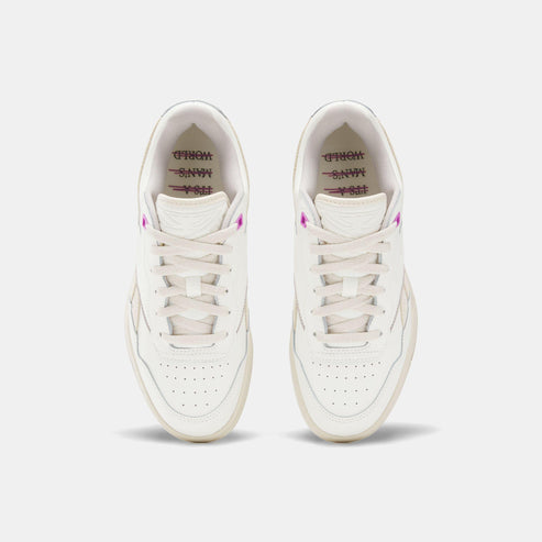 Top-down shot of two off-white sneakers with white laces, perforated toeboxes, and a splash of pink detail.