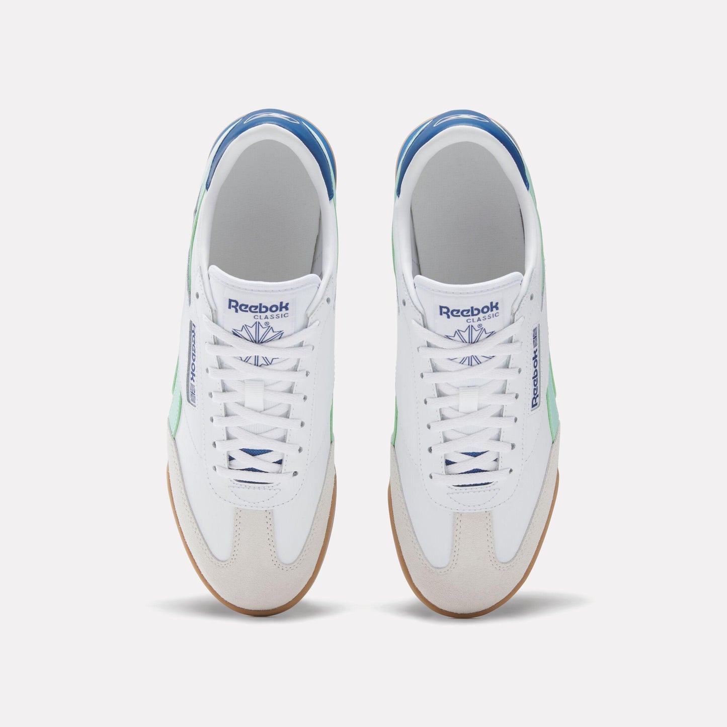 Top-down view of white sneakers with light green accents, blue trim, and gum soles.