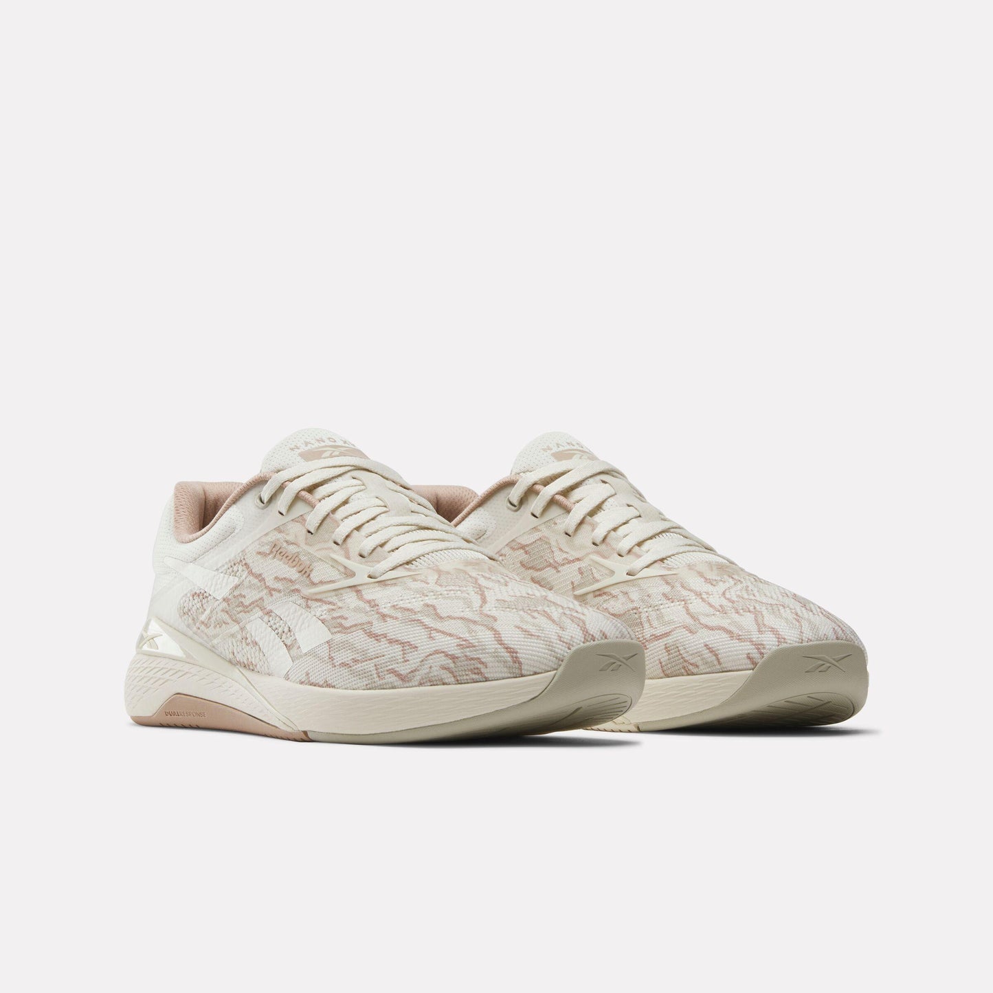 Pair of low top athletic shoes in neutral tones with a speckled or marbled design and light-colored laces.