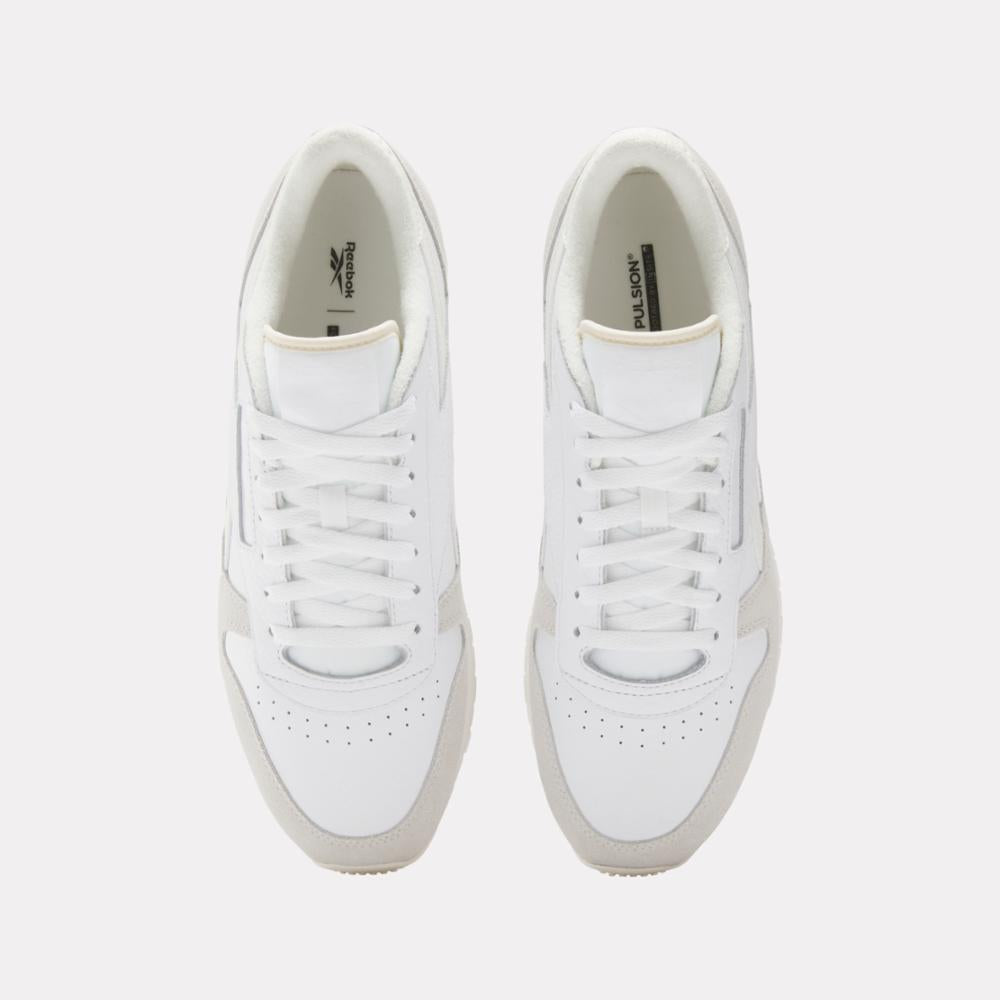 Overhead shot of two identical white sneakers with white laces.