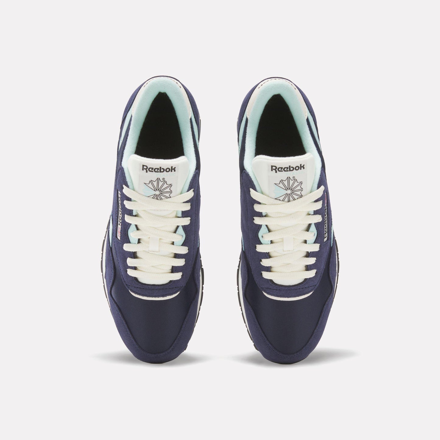 Overhead view of two navy Reebok Classics shoes, with cream laces, and pale green lining.