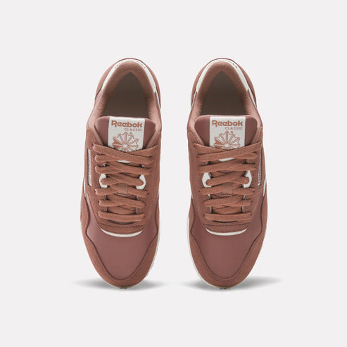 Top-down view of two brown athletic shoes with white shoe laces, brown fabric, and a visible logo on the tongue.
