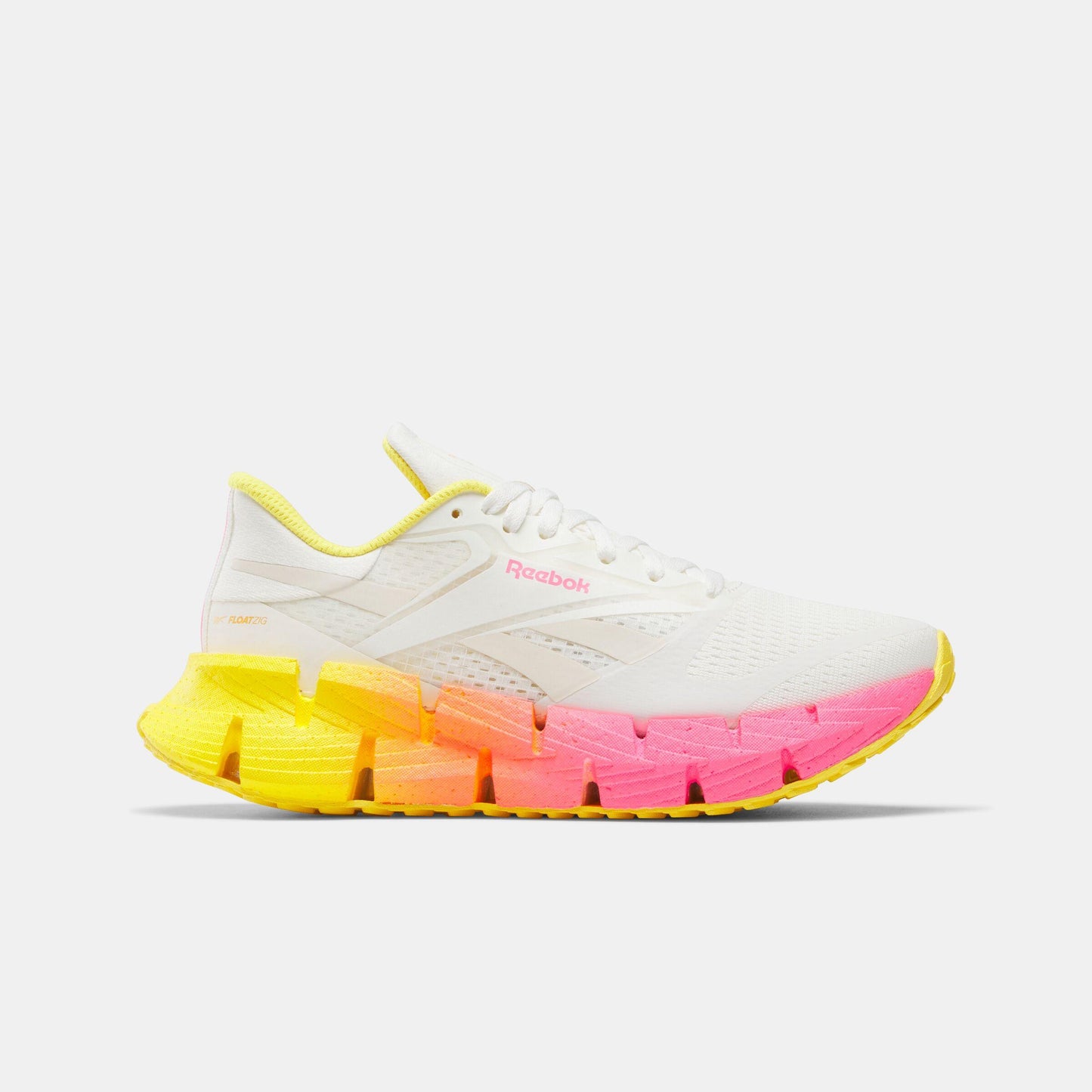 White running shoe with a yellow and pink gradient zigzag sole.  'Reebok' is printed on the side.