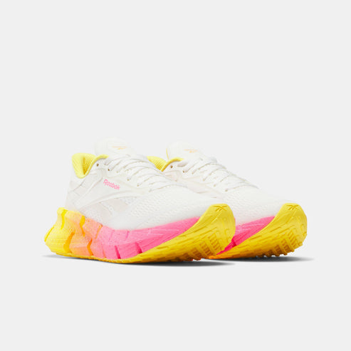 White running shoes with jagged pink and yellow soles.
