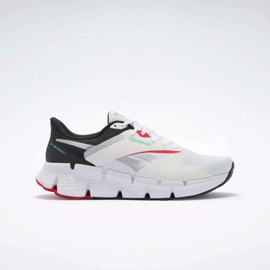 A white running shoe with red and silver accents has a black heel and white, ridged midsole.