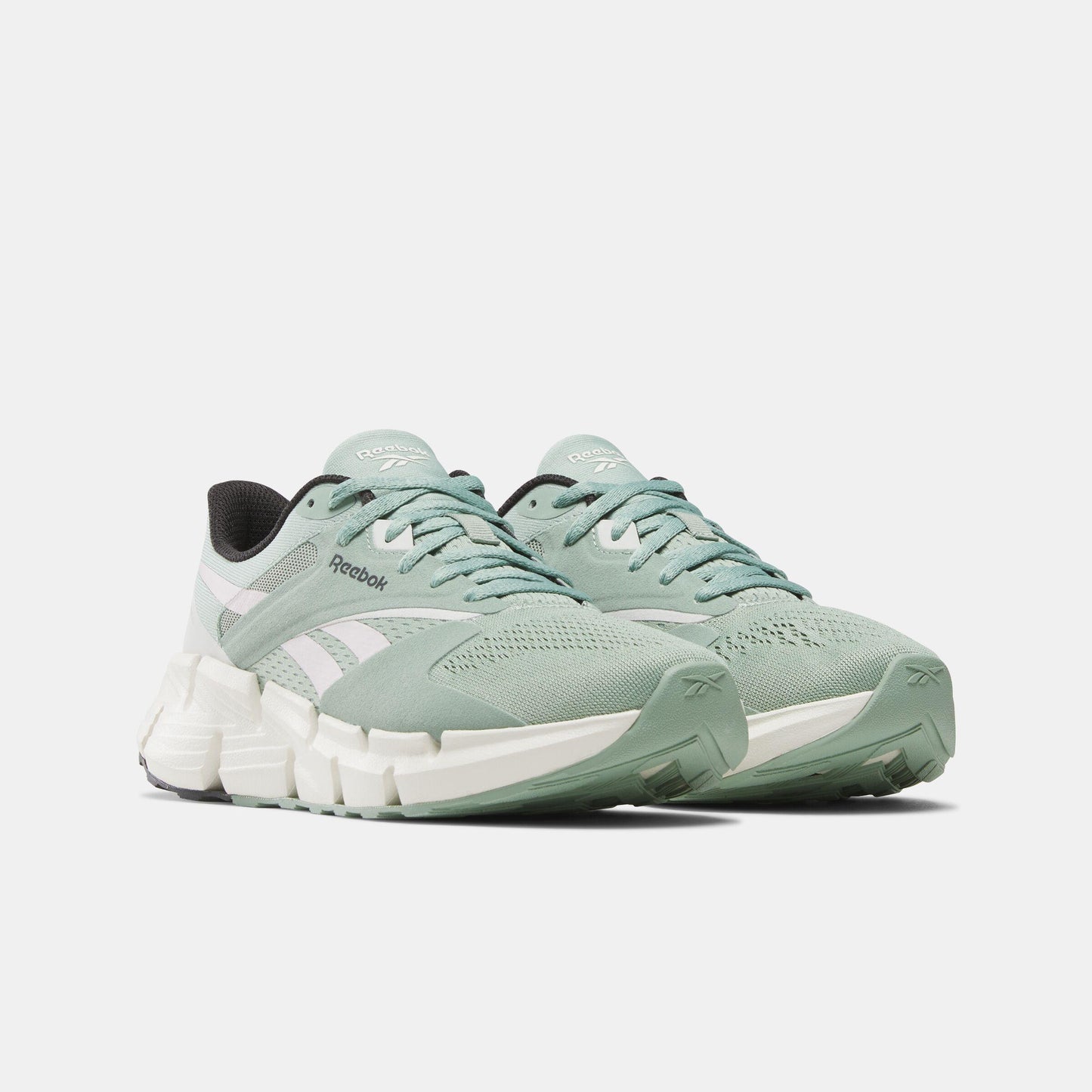 Pair of light green running shoes with white zigzag soles and black accents.