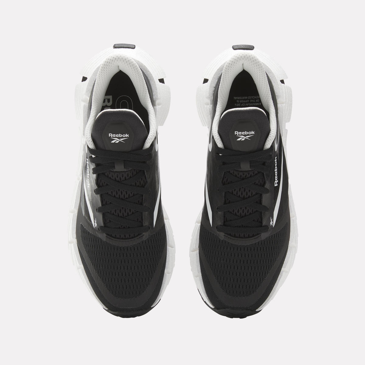 Top-down view of a pair of black athletic sneakers with white soles and accents, black laces and the Reebok logo on the tongue.