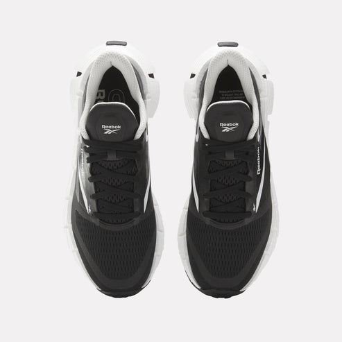 Top-down view of a pair of black athletic sneakers with white soles and accents, black laces and the Reebok logo on the tongue.