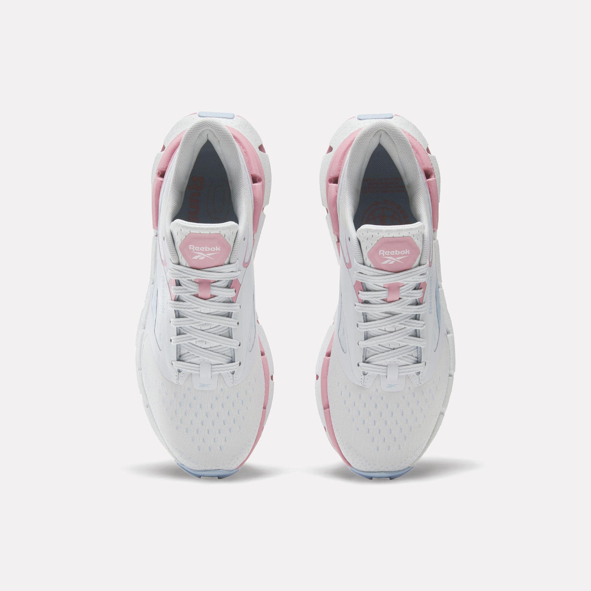 Top-down view of two identical white running shoes with pink accents, lace-up closure.