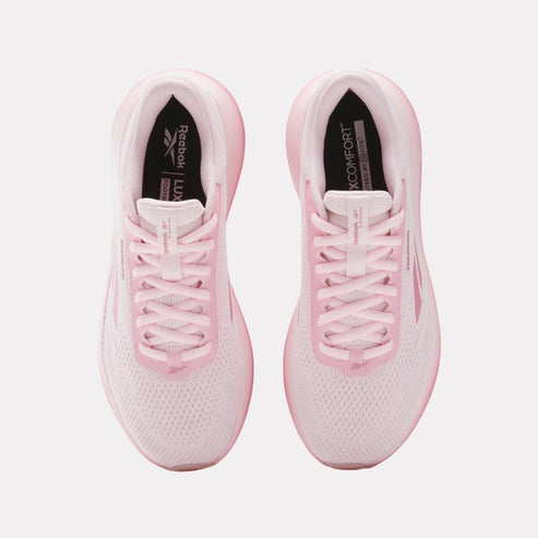 Overhead view of light pink running shoes, featuring white laces and ‘Reebok LUX’ text on the inner sole.