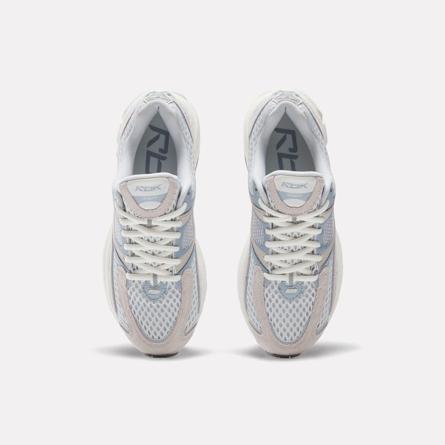 Top-down view of two identical white running shoes with white laces and grey accents, with "RBK" printed on the tongue.