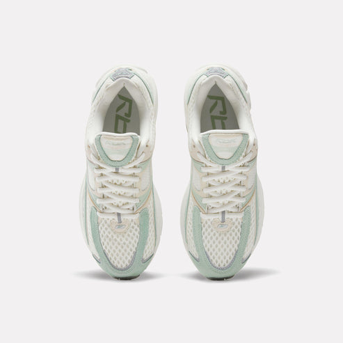 Pair of off-white sneakers with white laces and light green accents. The letters "RBK" are visible inside the shoe.