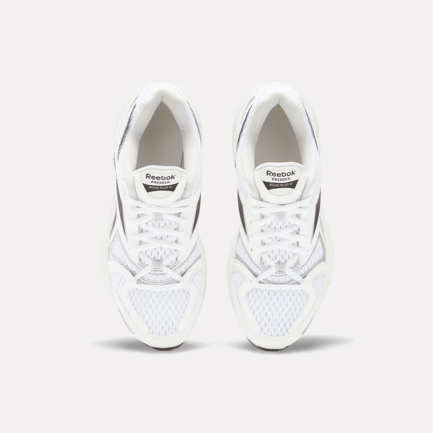 Pair of white sneakers with black accents, laces, and "Reebok" tag.