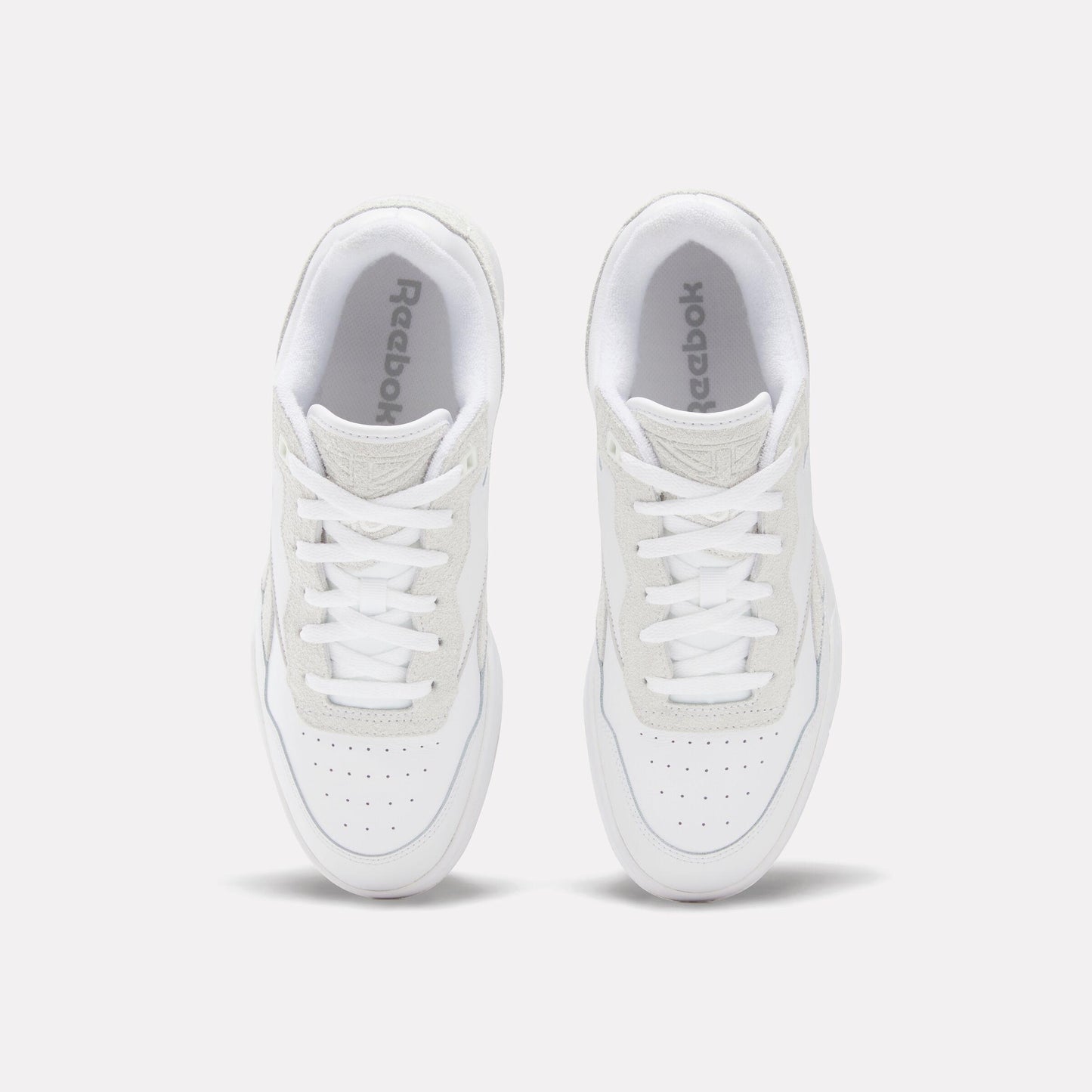 Overhead view of two white leather athletic shoes with white laces.