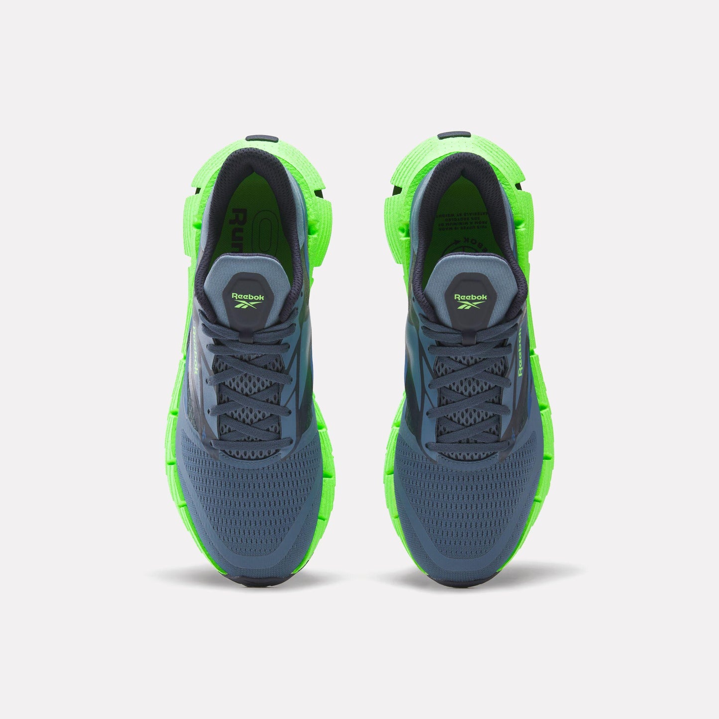 Top-down view of a pair of dark gray athletic shoes with green soles and accents.