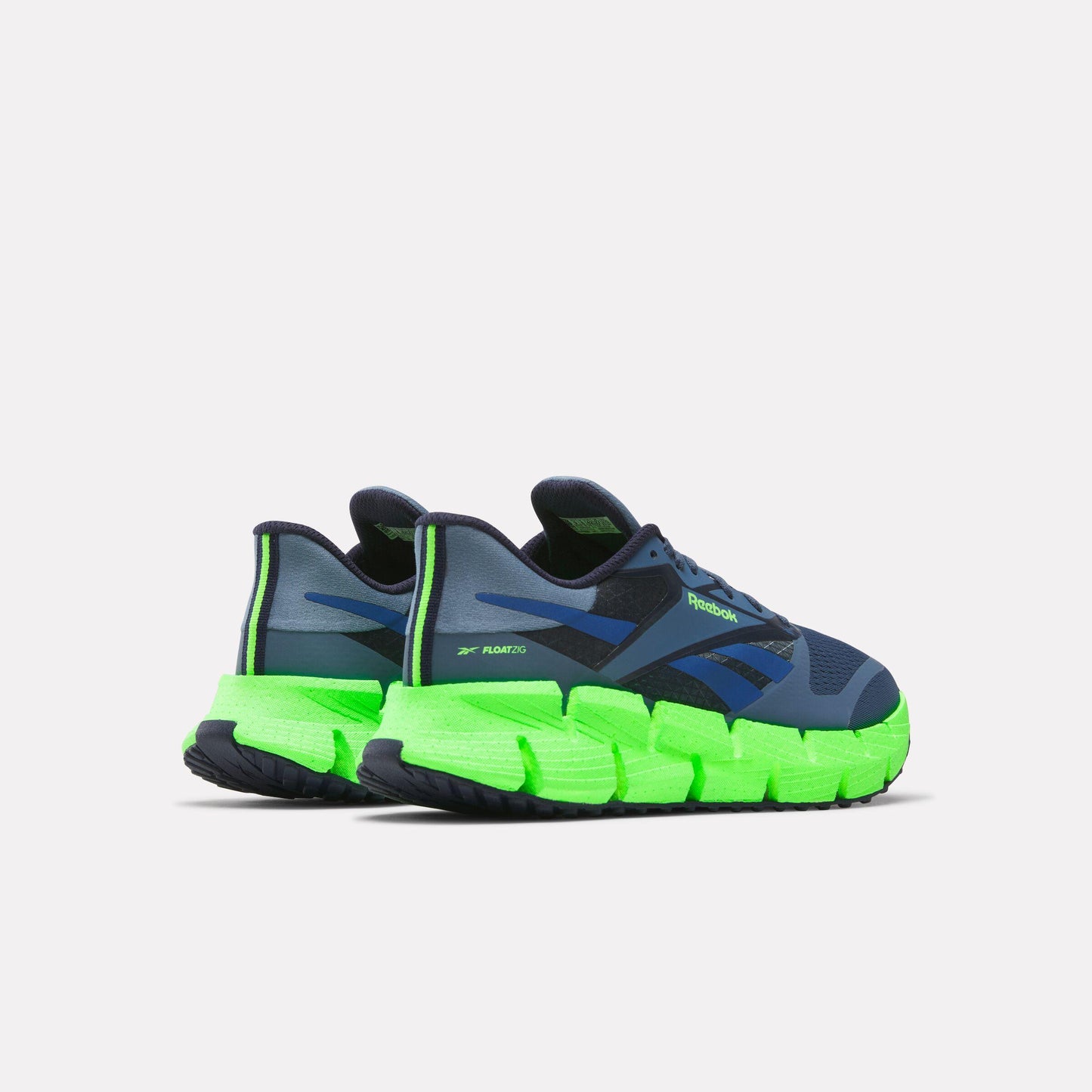 Low-top athletic shoes in dark blue, with green zigzag soles and green heel accent.
